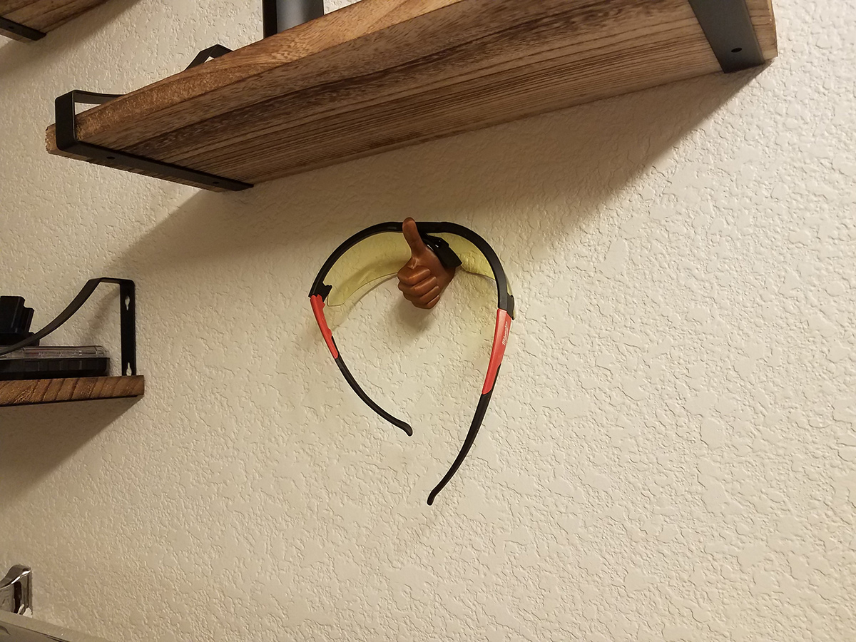 Thumbs up sculpture mounted on a wall holding headphones as a functional hanger